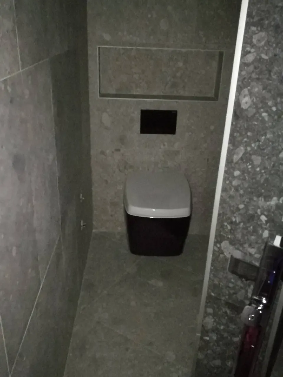 Crna konzolna WC šolja u kupatilu sa sivim pločicama